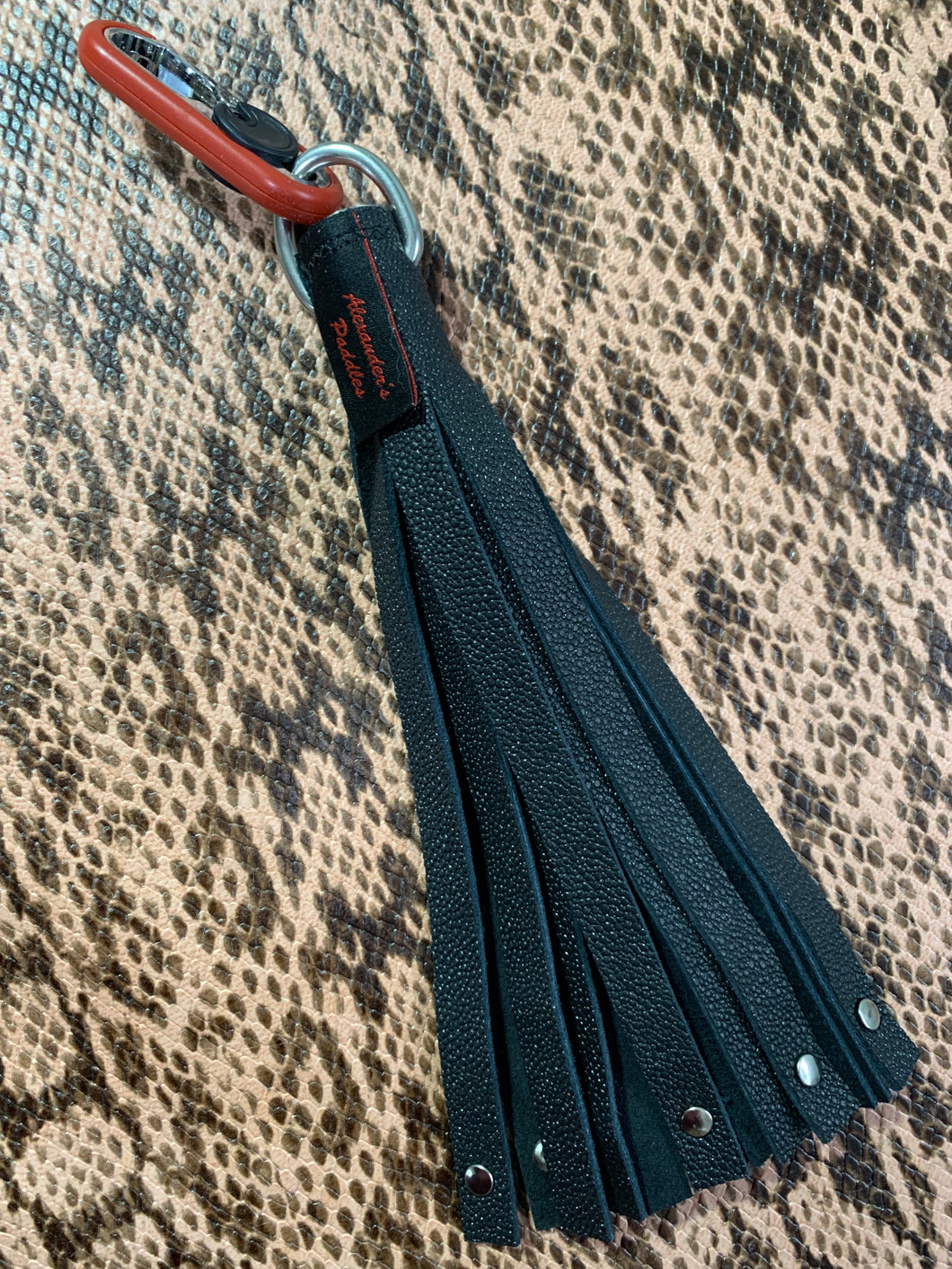 Flogger: black leather riveted key chain flogger with red metal fob